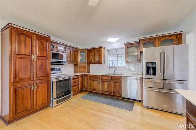 24 Shaw Ct, Cottleville Township, MO 63304 - kitchen featuring appliances with stainless steel finishes, a sink, light wood-type flooring, and brown cabinets