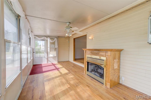 24 Shaw Ct, Cottleville Township, MO 63304 - unfurnished living room featuring a fireplace, ceiling fan, wood walls, and light wood-style flooring