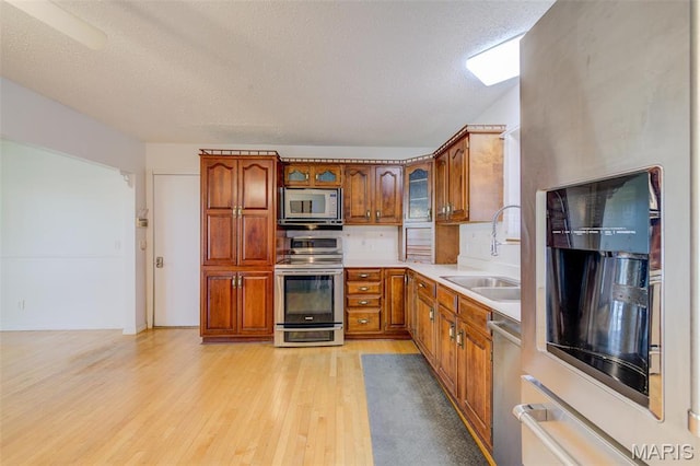 24 Shaw Ct, Cottleville Township, MO 63304 - kitchen with appliances with stainless steel finishes, a sink, light wood-type flooring, brown cabinets, and light countertops
