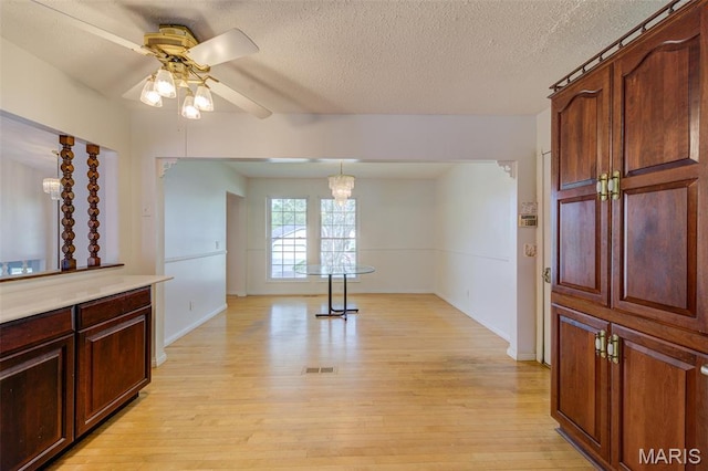 24 Shaw Ct, Cottleville Township, MO 63304 - unfurnished dining area with light wood-type flooring, a ceiling fan, a textured ceiling, a chandelier, and baseboards