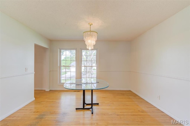 24 Shaw Ct, Cottleville Township, MO 63304 - unfurnished dining area featuring a textured ceiling, light wood finished floors, a chandelier, and baseboards