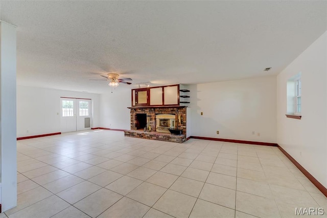 24 Shaw Ct, Cottleville Township, MO 63304 - unfurnished living room with a ceiling fan, a brick fireplace, light tile patterned floors, baseboards, and a textured ceiling