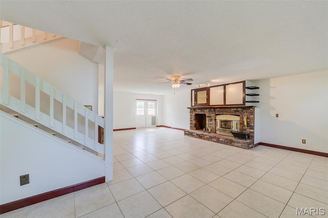 24 Shaw Ct, Cottleville Township, MO 63304 - unfurnished living room featuring stairs, ceiling fan, a fireplace, light tile patterned floors, and a textured ceiling