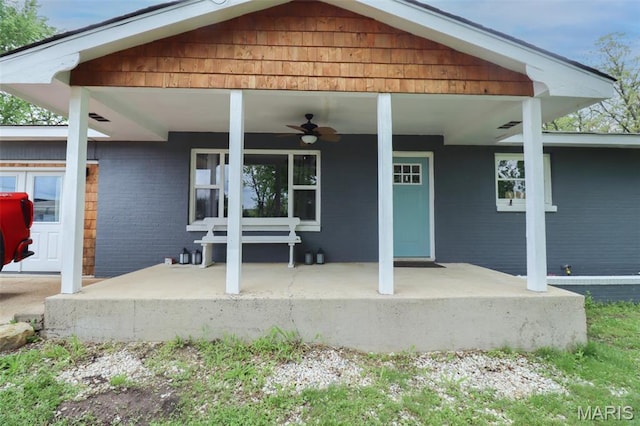 rear view of property featuring a ceiling fan, covered porch, and brick siding