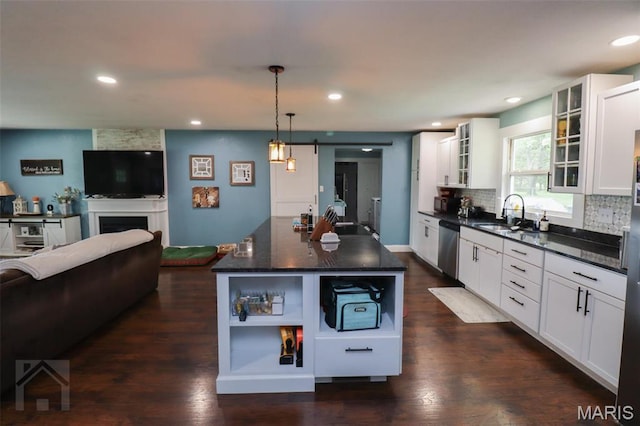 kitchen with dishwasher, a sink, white cabinets, a barn door, and glass insert cabinets