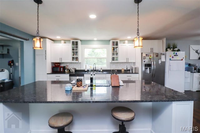 kitchen with appliances with stainless steel finishes, a large island, backsplash, white cabinetry, and recessed lighting