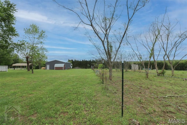 view of green lawn with a garage, an outdoor structure, an outbuilding, and a rural view