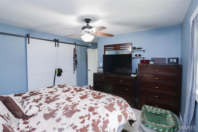 bedroom with a barn door and ceiling fan