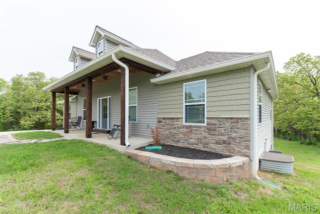 5814 Calvey Creek Rd, Robertsville, MO 63072 - view of side of home with a yard, stone siding, a patio area, and roof with shingles