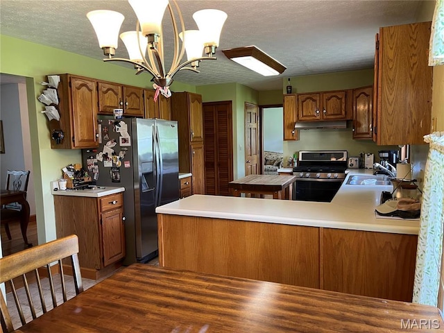 1235 S Hackman St, Staunton, IL 62088 - kitchen with appliances with stainless steel finishes, under cabinet range hood, a chandelier, wood finished floors, and light countertops