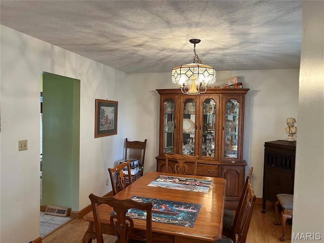 1235 S Hackman St, Staunton, IL 62088 - dining area with a chandelier, light wood finished floors, and a textured ceiling