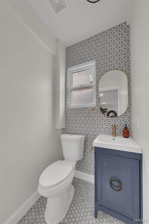 6815 Wise Ave, Saint Louis, MO 63139 - bathroom with wallpapered walls, baseboards, toilet, vanity, and tile patterned flooring