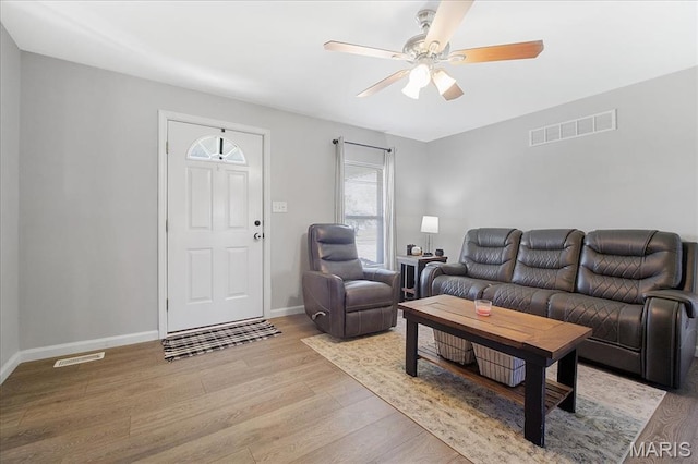 living room featuring wood finished floors, a ceiling fan, and baseboards