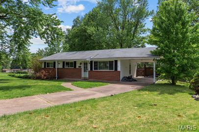 1605 Koch Dr, Florissant, MO 63033 - ranch-style house with concrete driveway, a front yard, and a carport