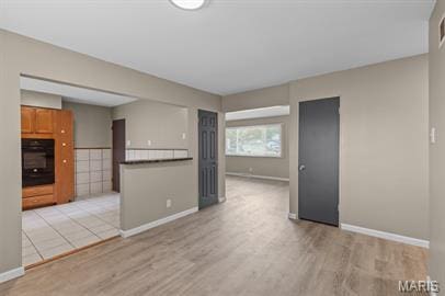 1605 Koch Dr, Florissant, MO 63033 - unfurnished living room with light wood-style flooring and baseboards