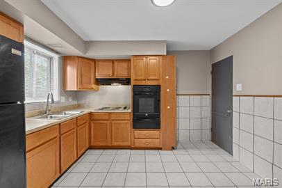 1605 Koch Dr, Florissant, MO 63033 - kitchen with black appliances, a warming drawer, a sink, light countertops, and under cabinet range hood