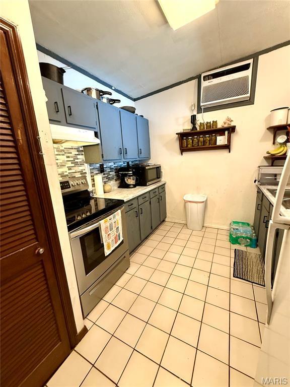 56 Berger Rd, Middletown, MO 63359 - kitchen featuring stainless steel appliances, under cabinet range hood, an AC wall unit, light tile patterned floors, and light countertops