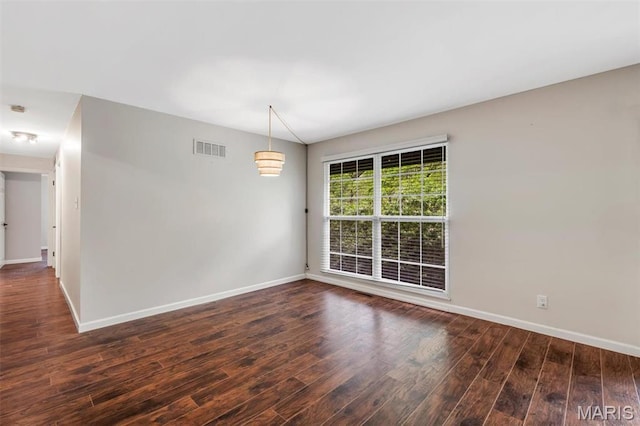 spare room featuring baseboards and wood finished floors