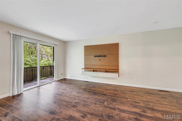 unfurnished living room featuring wood finished floors and baseboards