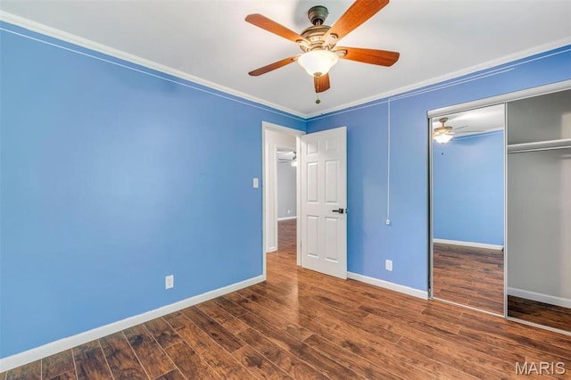 unfurnished bedroom featuring baseboards, wood finished floors, a closet, crown molding, and ceiling fan
