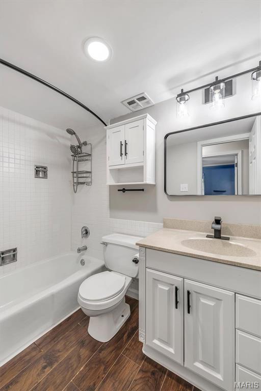 full bathroom with vanity, wood finished floors, toilet, and washtub / shower combination