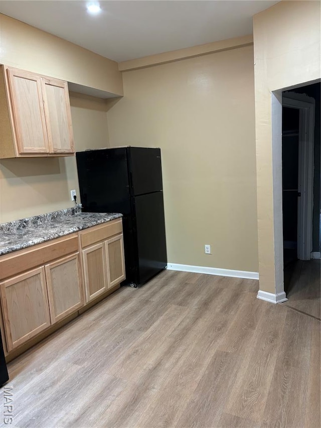 4844 Northland Ave, Saint Louis, MO 63113 - kitchen featuring freestanding refrigerator, light brown cabinetry, light wood finished floors, baseboards, and light stone countertops