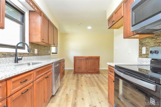 19 Ruth Ann Dr, Godfrey, IL 62035 - kitchen with appliances with stainless steel finishes, a sink, decorative backsplash, light wood finished floors, and light stone counters