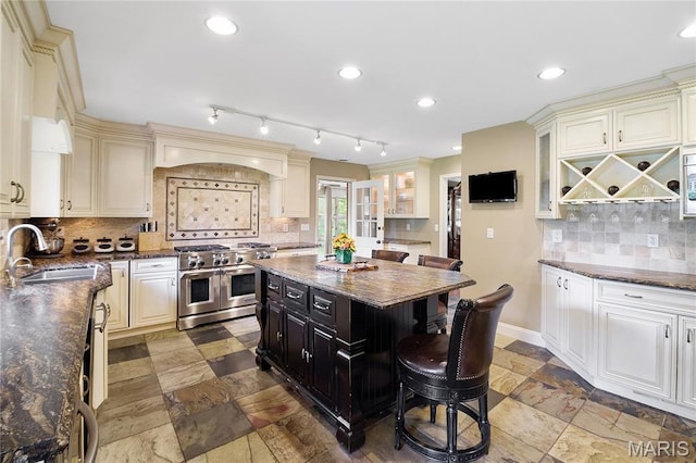 12935 Topping Estates Dr, Town And Country, MO 63131 - kitchen featuring range with two ovens, a sink, tasteful backsplash, glass insert cabinets, and stone tile flooring