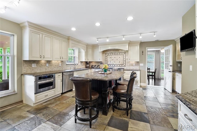 12935 Topping Estates Dr, Town And Country, MO 63131 - kitchen with appliances with stainless steel finishes, stone tile floors, cream cabinetry, healthy amount of natural light, and recessed lighting