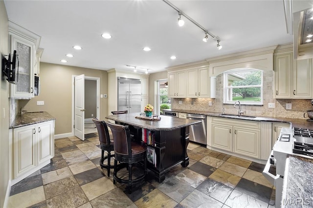 12935 Topping Estates Dr, Town And Country, MO 63131 - kitchen with stainless steel appliances, a sink, cream cabinets, backsplash, and dark stone counters