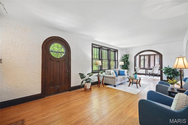7350 Colgate Ave, University City, MO 63130 - living room featuring a textured wall, wood finished floors, arched walkways, and baseboards