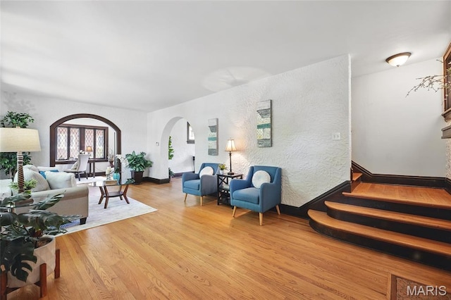 7350 Colgate Ave, University City, MO 63130 - living room with arched walkways, wood finished floors, stairs, and baseboards