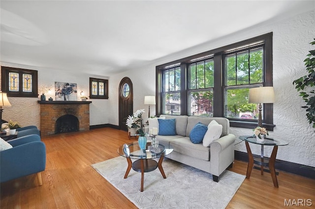 7350 Colgate Ave, University City, MO 63130 - living room with a textured wall, wood finished floors, a brick fireplace, and baseboards