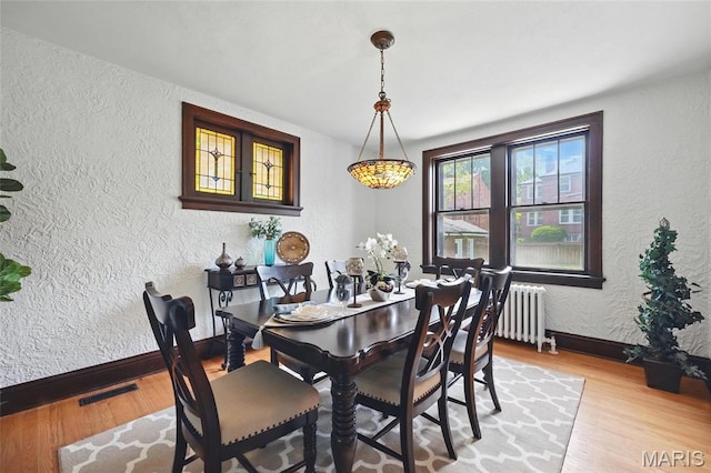 7350 Colgate Ave, University City, MO 63130 - dining space featuring a textured wall, radiator heating unit, wood finished floors, and baseboards