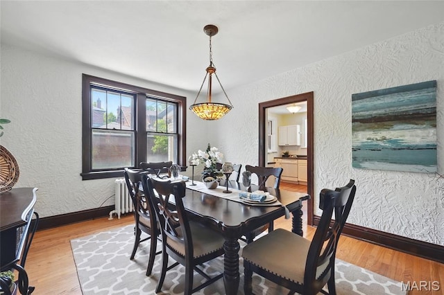 7350 Colgate Ave, University City, MO 63130 - dining space featuring a textured wall, radiator heating unit, light wood-style floors, and baseboards