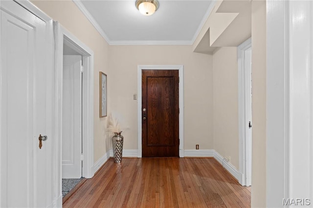 foyer with light wood-type flooring, baseboards, and crown molding