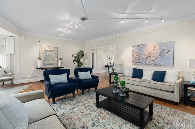 living area featuring rail lighting, wood finished floors, and ornamental molding
