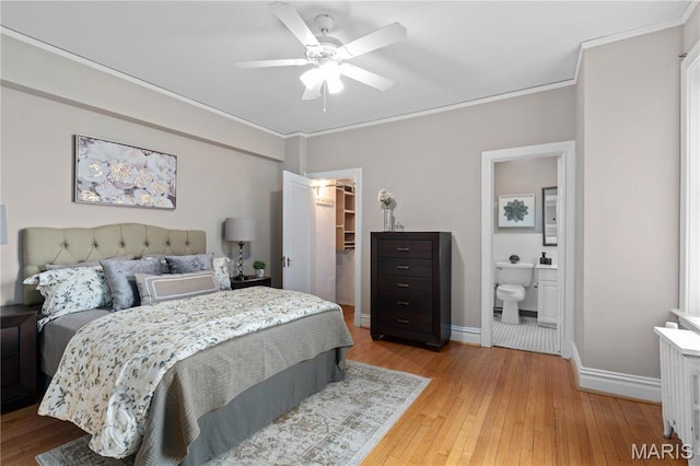 bedroom with radiator, a walk in closet, baseboards, ornamental molding, and light wood-type flooring