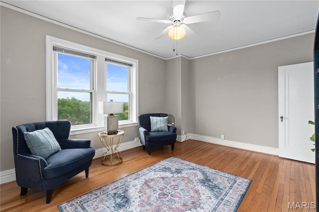 sitting room featuring light wood-type flooring, baseboards, ornamental molding, and ceiling fan