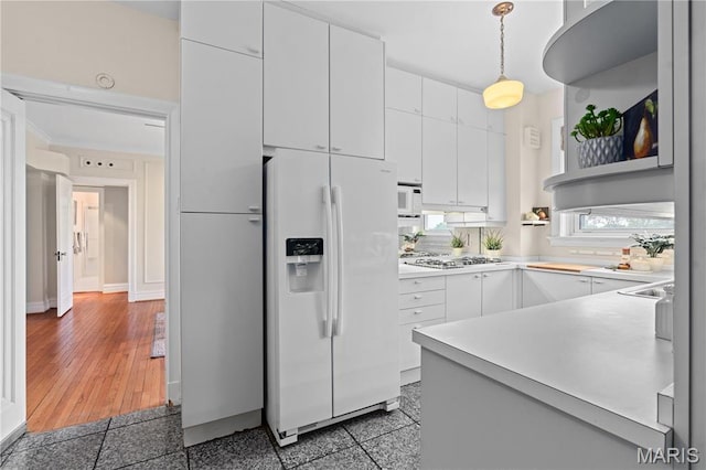 kitchen featuring white refrigerator with ice dispenser, stainless steel gas stovetop, light countertops, and white cabinets