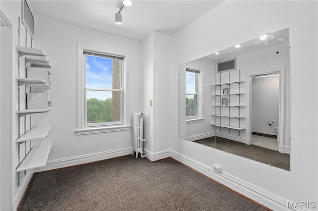 empty room featuring radiator heating unit, carpet floors, and baseboards