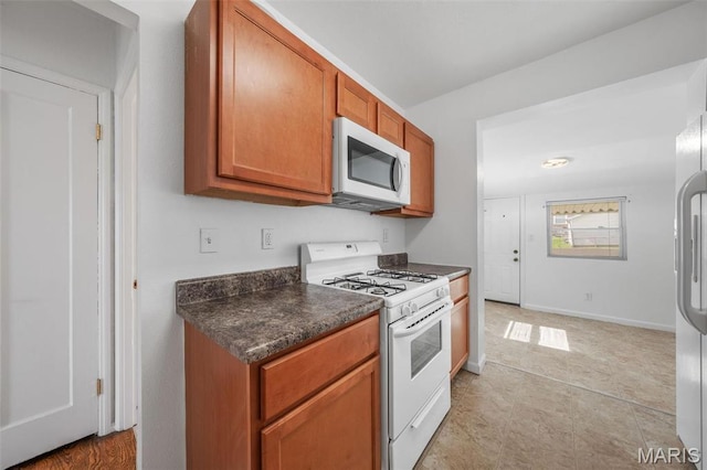 336 Tacoma Dr, Saint Louis, MO 63125 - kitchen with white appliances, dark countertops, and brown cabinetry