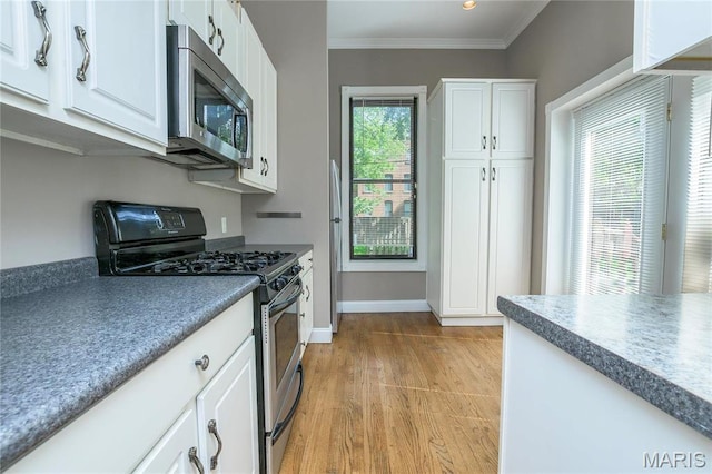 1703 Carroll St, Saint Louis, MO 63104 - kitchen with appliances with stainless steel finishes, baseboards, white cabinetry, light wood-style floors, and ornamental molding