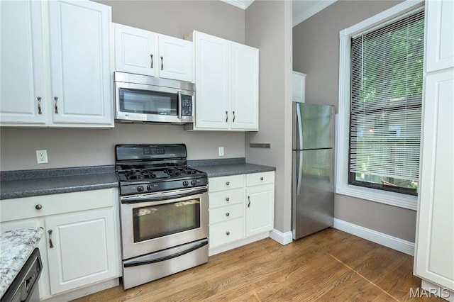 1703 Carroll St, Saint Louis, MO 63104 - kitchen featuring appliances with stainless steel finishes, light wood finished floors, white cabinetry, and ornamental molding