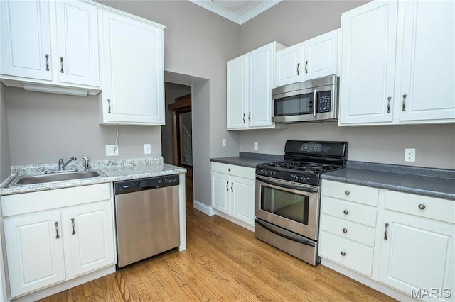 1703 Carroll St, Saint Louis, MO 63104 - kitchen featuring stainless steel appliances, a sink, crown molding, light wood-style flooring, and white cabinets