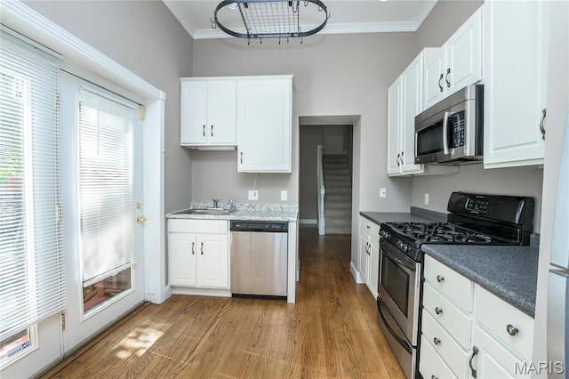 1703 Carroll St, Saint Louis, MO 63104 - kitchen with appliances with stainless steel finishes, crown molding, a sink, light wood finished floors, and white cabinetry