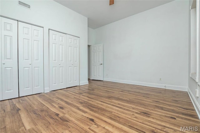1703 Carroll St, Saint Louis, MO 63104 - unfurnished bedroom featuring multiple closets, wood finished floors, baseboards, and a ceiling fan