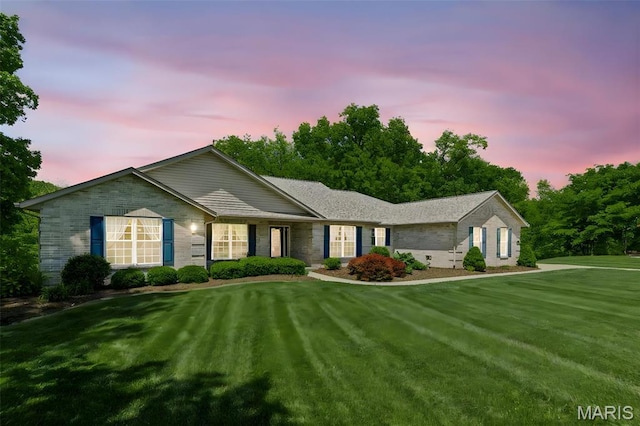 ranch-style house featuring brick siding and a yard