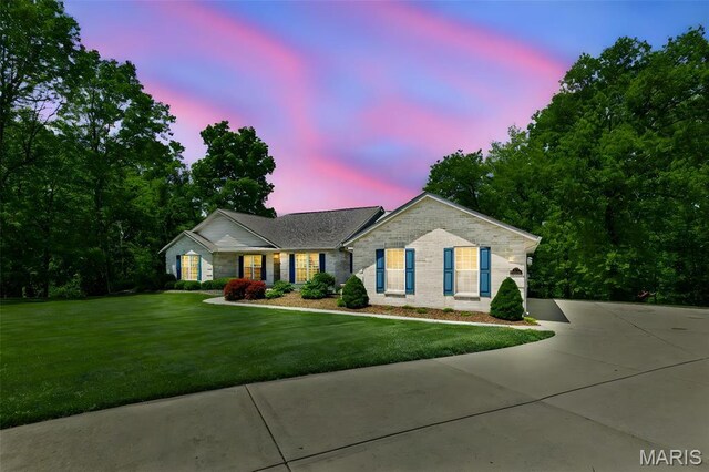 ranch-style house featuring a lawn, brick siding, and concrete driveway