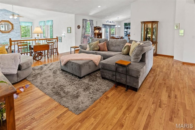 living area with vaulted ceiling, plenty of natural light, light wood-type flooring, and baseboards